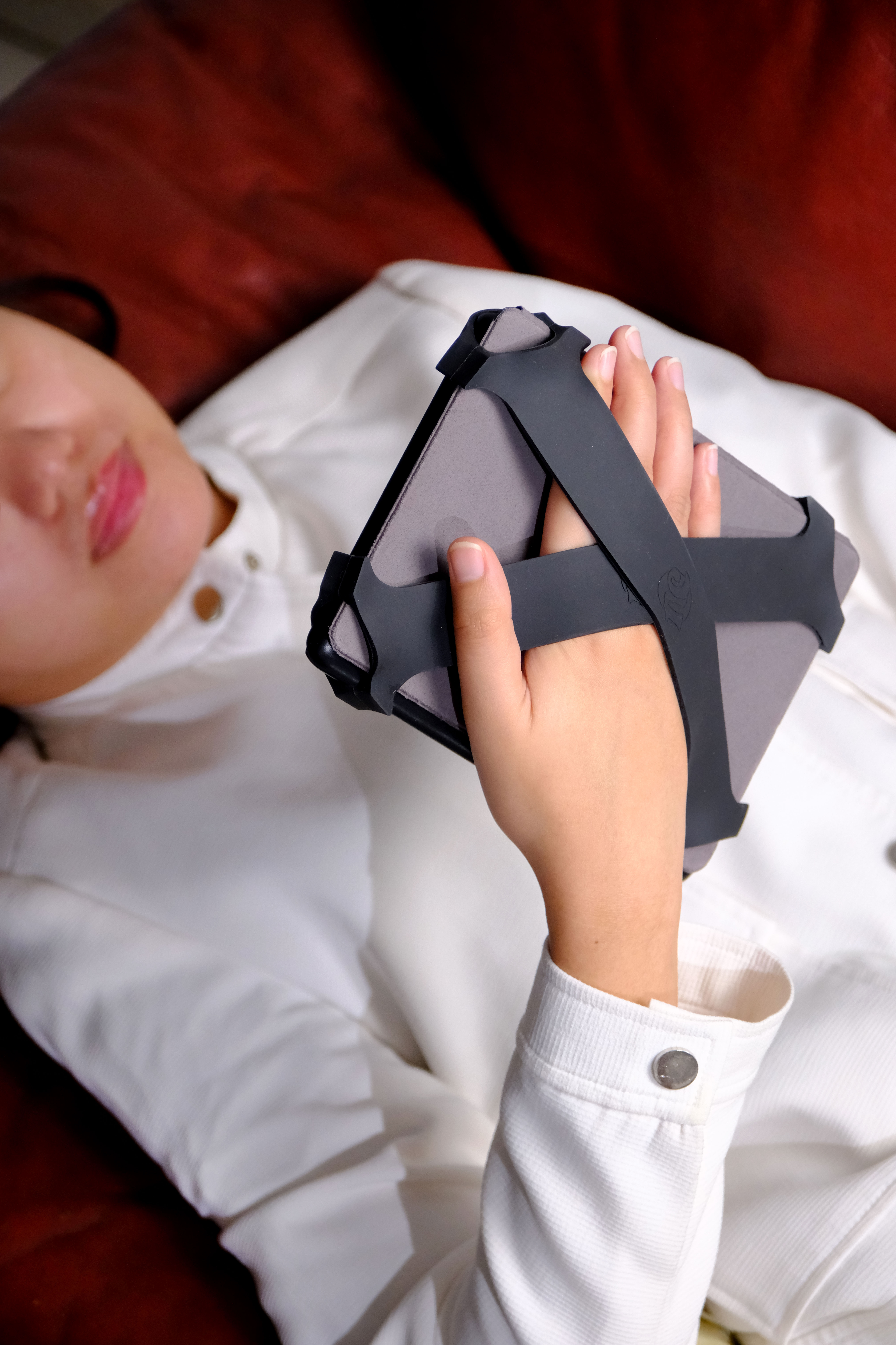 Reader reclining with a Kindle secured by midnight straps